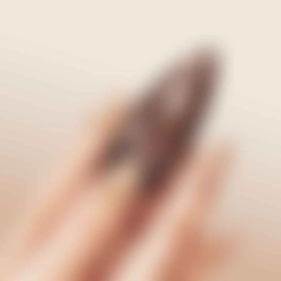 Applying a glossy top coat over a nail design on an almond shaped nail